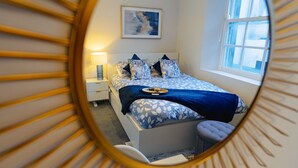 Een slaapkamer met een bed, nachtkastje, lamp en een raam.