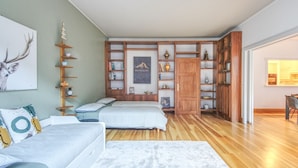 Une chambre avec deux lits, une bibliothèque en bois et une grande fenêtre.