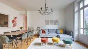 Un salon moderne comprenant un coin repas, un ensemble de canapés et un lustre.