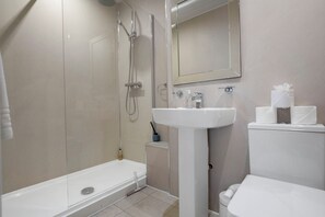 A modern bathroom with a shower, toilet, sink, and mirror.