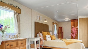Een slaapkamer met een houten bed, een dressoir, een nachtkastje en een raam met gordijnen.