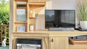 Een houten tv-meubel met een flatscreen televisie, een klein plantje en een ingelijst foto.