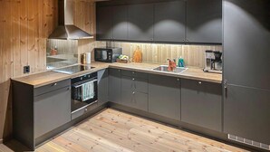 Une cuisine moderne avec des meubles en bois, un four encastré, un four à micro-ondes et une machine à café.