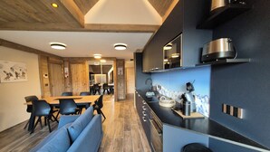 Una cocina moderna con estufa integrada, lavamanos y comedor con una mesa grande y asientos azules.