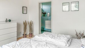 Une chambre à coucher comprenant un lit, une commode et une porte donnant sur une salle de bain.