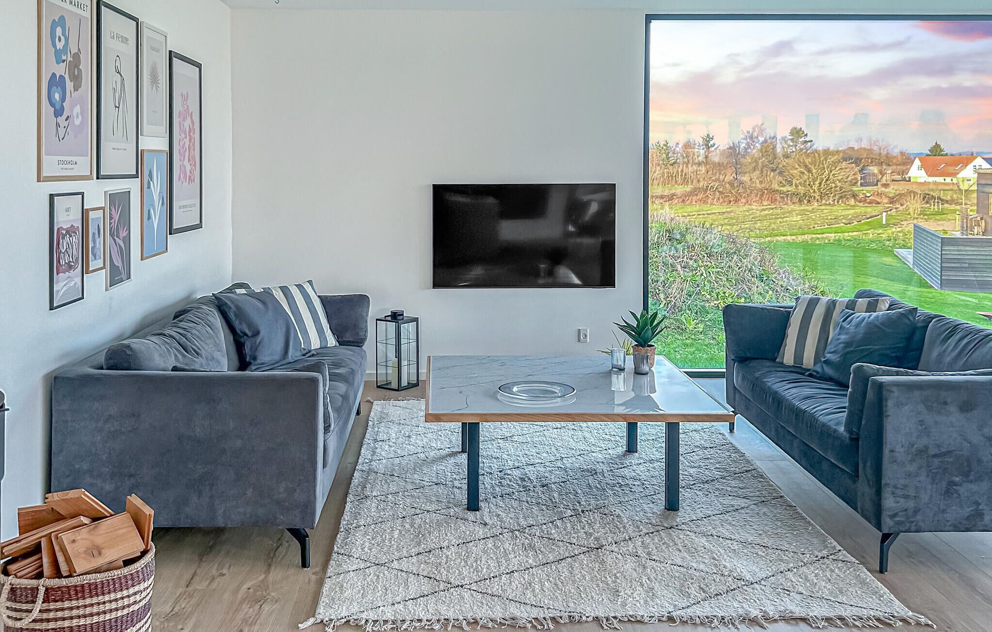 Ein modernes Wohnzimmer mit zwei grauen Sofas, einem Couchtisch und einem großen Fernseher.