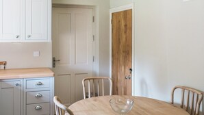 Un comedor con una mesa redonda de madera, cuatro sillas y un mueble con cajones.