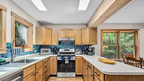Una cocina moderna con armarios de madera, una estufa de acero inoxidable y un amplio ventanal que proporciona luz natural.