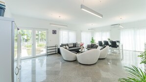 A modern living room with a sofa set, a dining area, and a view of the outdoors. - Beautiful home in Privlaka (Privlaka)