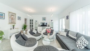 A modern living room with a sofa, chairs, a TV, and artwork on the walls. - Beautiful home in Privlaka (Privlaka)