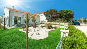 A modern house with a tiled roof, a well-maintained garden, and a parked car in the background. - Beautiful home in Privlaka (Privlaka)