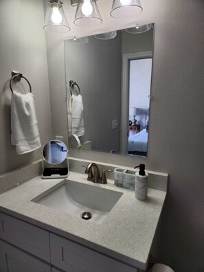 A bathroom with a large mirror, a sink, and two towel rings. - Apartment in the heart  of Historic Ocala Downtown  (Ocala)