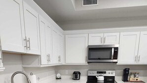 Una cocina moderna con armarios blancos, electrodomésticos de acero inoxidable y suelo de madera.
