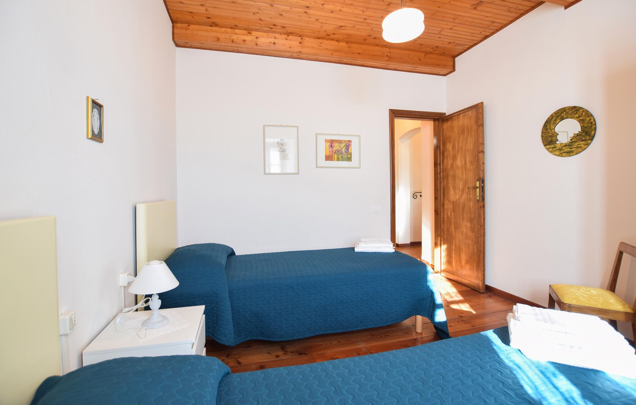 Ein Schlafzimmer mit zwei Betten, einer Holzbalkendecke und einer Tür zu einem anderen Raum.