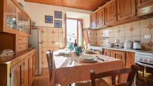 A kitchen with wooden cabinets, a dining table set for four, and a stove. - Gorgeous home in Farnocchia with WiFi (Farnocchia)