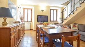 A cozy dining area with a wooden table and chairs, a television, and a staircase. - Gorgeous home in Farnocchia with WiFi (Farnocchia)