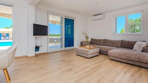 A modern living room with a sofa, a coffee table, and a TV mounted on the wall. - Stunning home in Privlaka with private swimming pool, can be inside or outside (Privlaka)