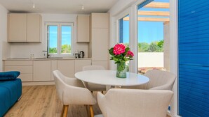 A modern kitchen with a dining area, featuring a round table and chairs, a coffee maker, and a vase with flowers. - Stunning home in Privlaka with private swimming pool, can be inside or outside (Privlaka)