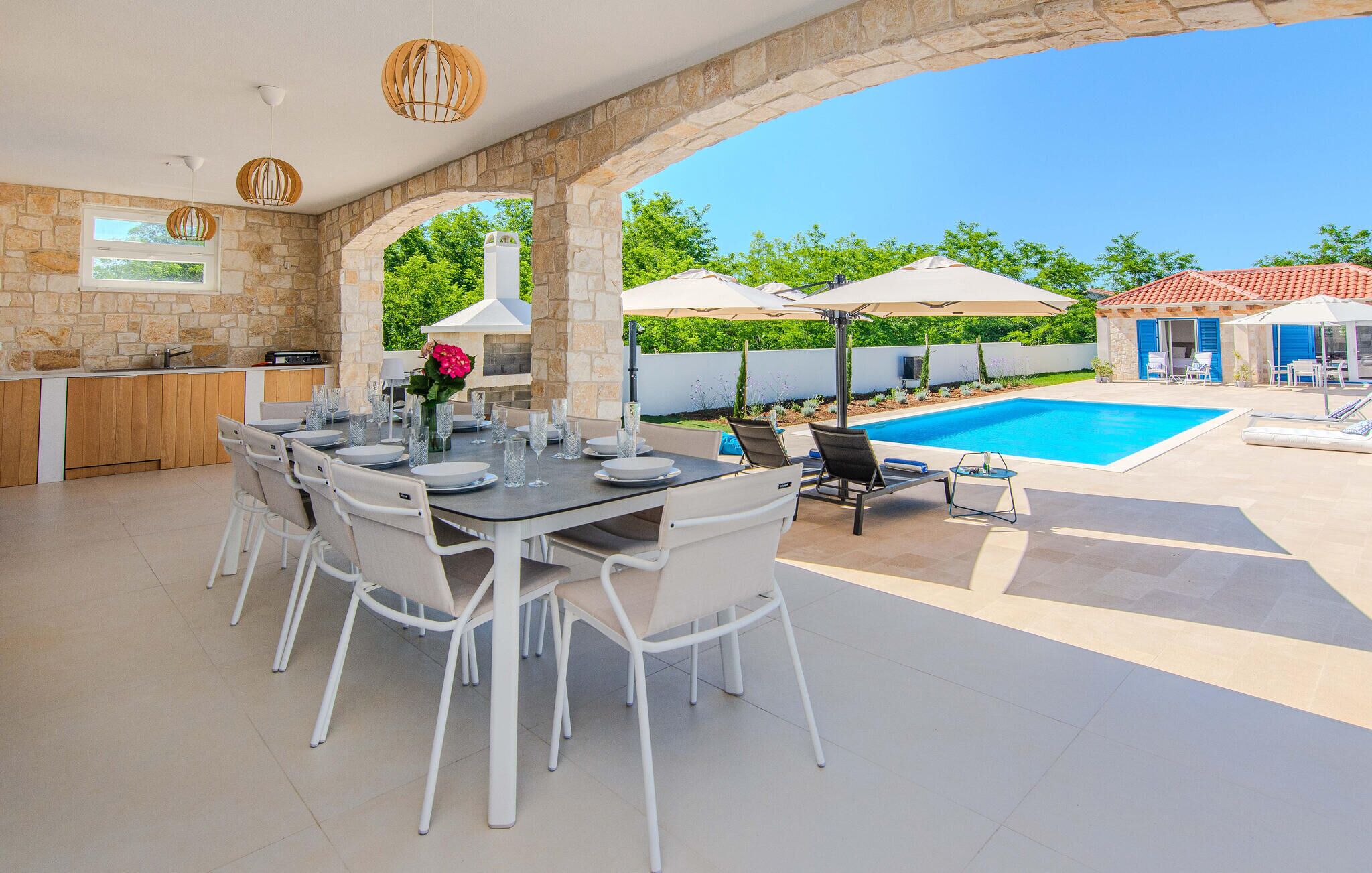 Un espace extérieur abrité où l’on peut prendre ses repas, avec une piscine en arrière-plan.