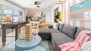 Una sala de estar acogedora con una mesa de fútbol de mesa, una torre de Jenga y un mural colorido en la pared.