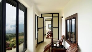 A corridor with sliding doors leading to a balcony with a view of the mountains. - Ibex Resorts, Valparai (Tale Rock) (Valparai)