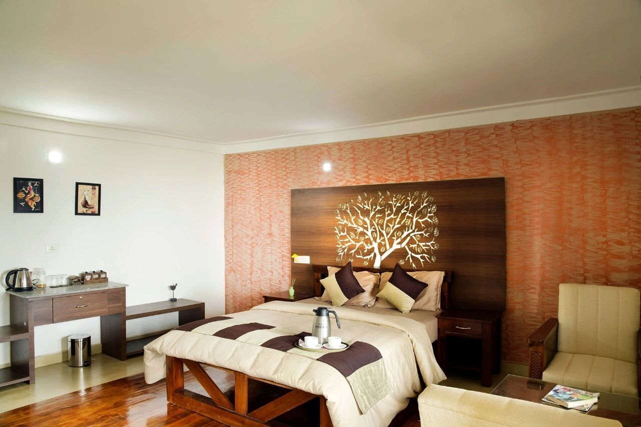 A hotel room with a bed, bedside table, chair, and a decorative wall panel.