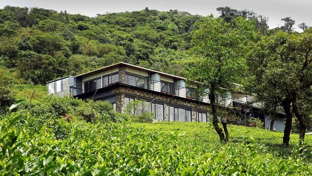 A modern building with a balcony overlooking a lush green tea plantation. - Ibex Resorts, Valparai (Tale Rock) (Valparai)