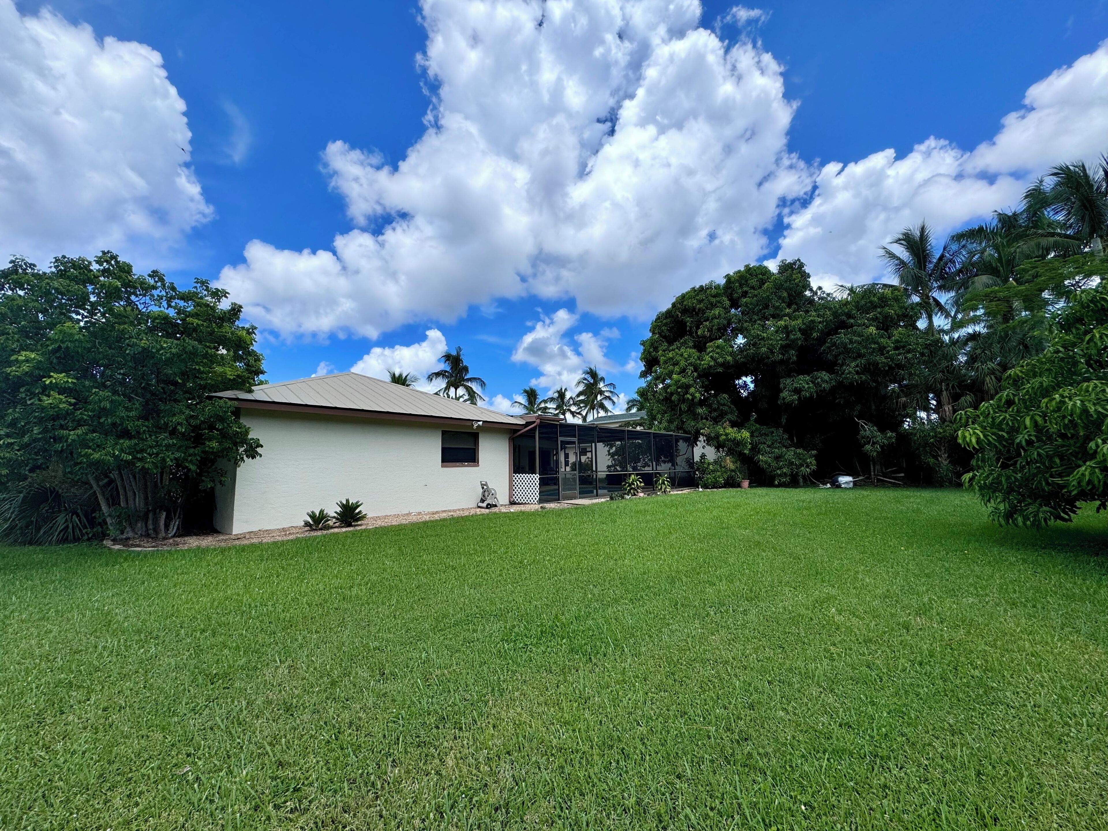 A house with a well-maintained lawn, a covered porch, and a large tree in the background.