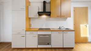 A kitchen with white cabinets, a wooden countertop, a built-in oven, and a sink. - Studio 'Waldheim Apt 4' with Mountain View, Shared Garden and Wi-Fi (Ahrntal)