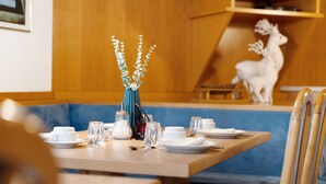 A dining table set with white plates, glasses, and a vase with greenery. - Studio 'Waldheim Apt 4' with Mountain View, Shared Garden and Wi-Fi (Ahrntal)