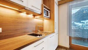 Eine moderne Küche mit einer Holz Arbeitsplatte, einer Edelstahl-Spüle und einer Mikrowelle.