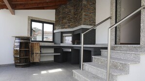 A modern kitchen with a stone fireplace, a wooden barrel, and a staircase with metal railings. - Holiday Home 'Casa Do Lagar' with Mountain View, Wi-Fi and Air Conditioning (Agilde)