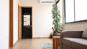 A living room with a sofa, a potted plant, a window, and an air conditioning unit. - Holiday Home 'Casa Do Lagar' with Mountain View, Wi-Fi and Air Conditioning (Agilde)
