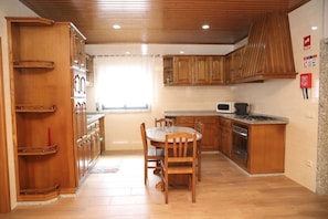 Una cocina con armarios de madera, una mesa de comedor, sillas, un microondas, una estufa y un ventanal.