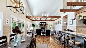 Una cocina amplia con vigas de madera, una zona de comedor con una mesa grande y una barra con taburetes.