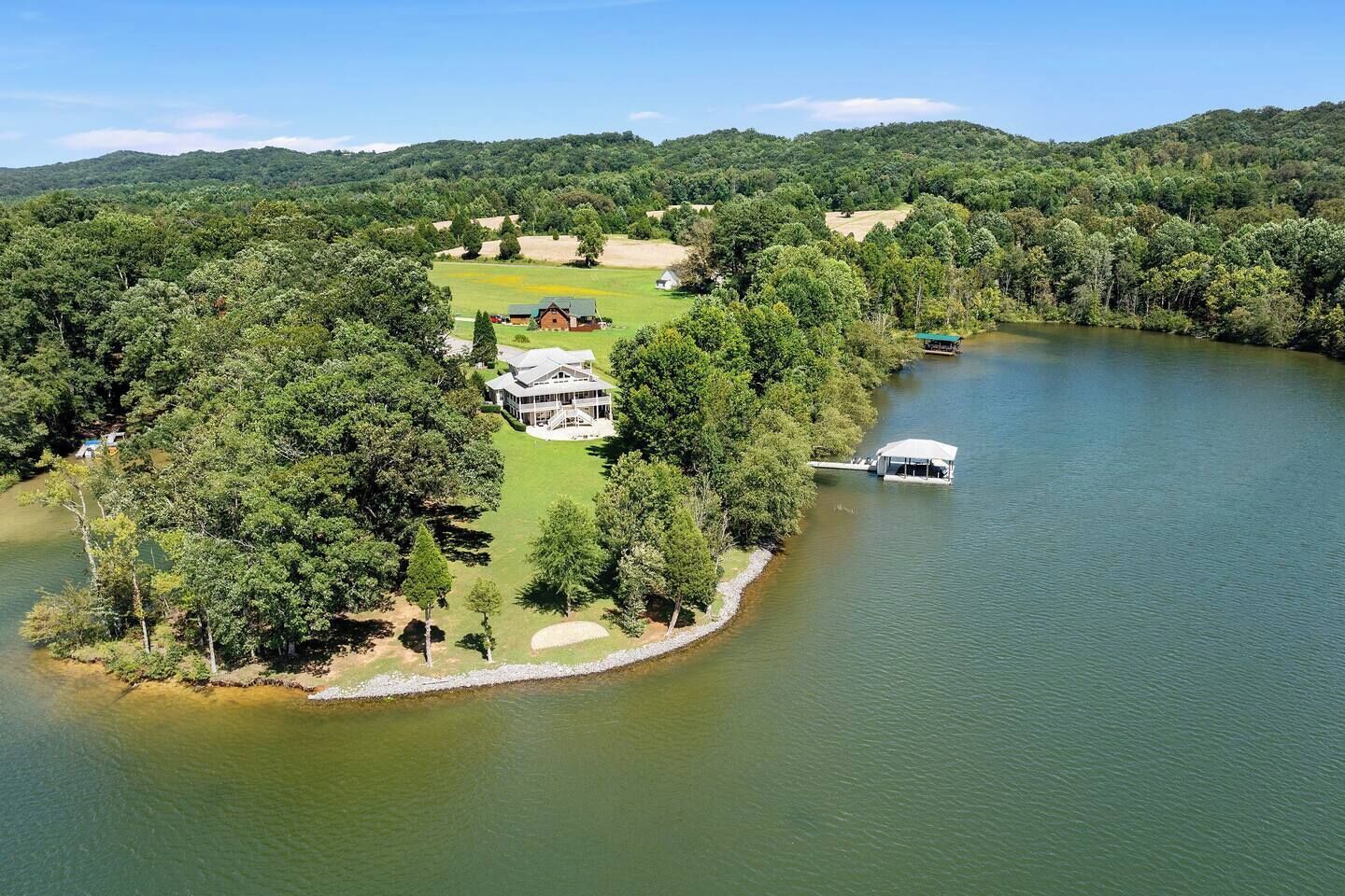 Une propriété au bord du lac comprenant une grande maison, un quai et un bateau.