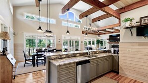 Una cocina amplia con una isla grande, vigas de madera y encimera de piedra.