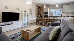 Un salon moderne doté d’un téléviseur à écran plat, d’un canapé, d’une table basse et d’un coin repas avec des chaises et une table.