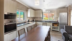 Une cuisine moderne dotée d’appareils électroménagers intégrés, d’un coin repas et offrant une vue sur l’extérieur.