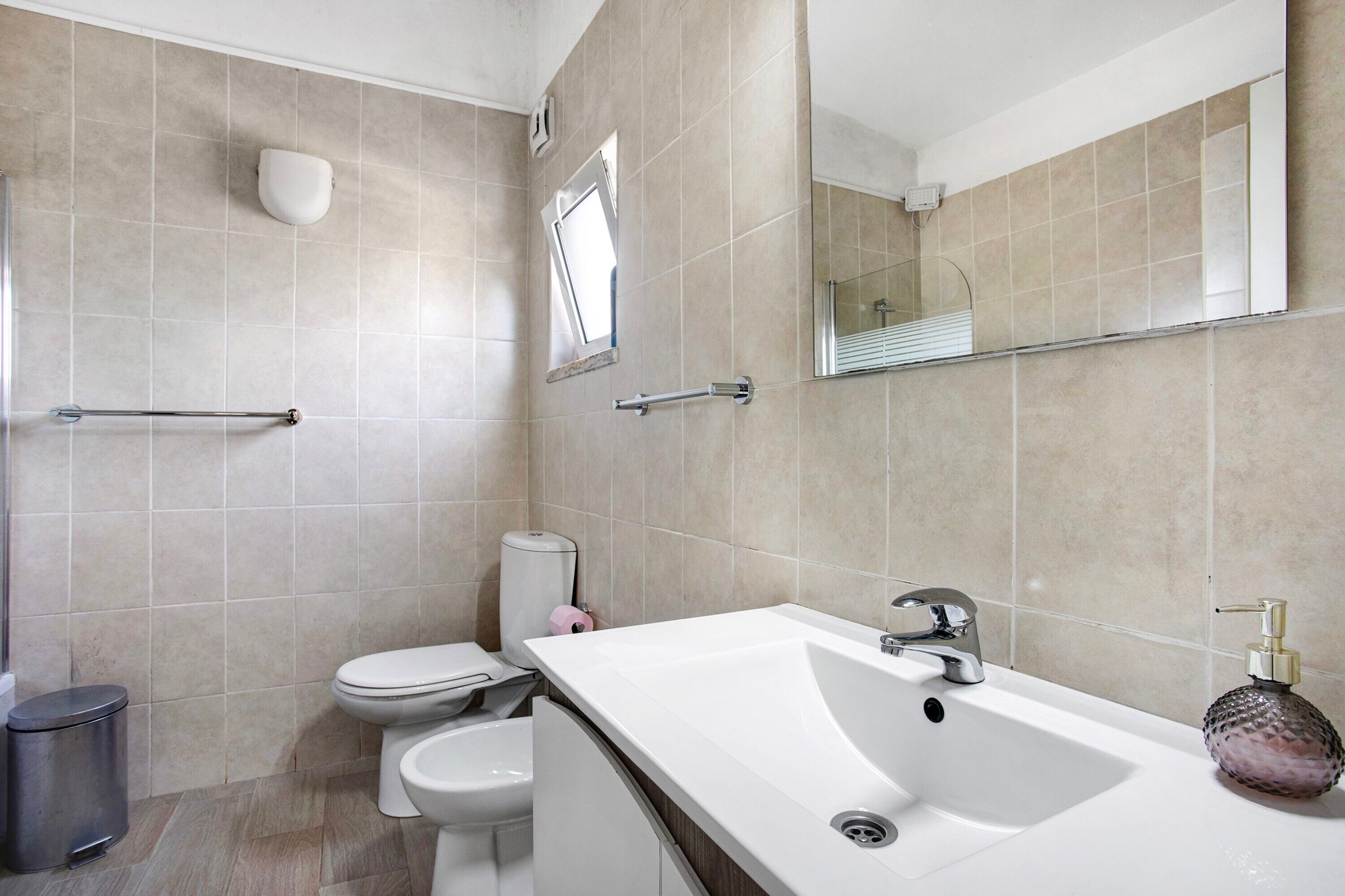 Ein Badezimmer mit einem weißen Waschbecken, einem Spiegel und einer Toilette.