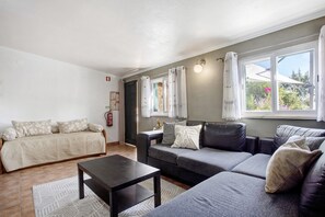 A living room with a sofa, a coffee table, and a window with curtains. - Holiday Home 'Casa 2' with Shared Pool, Wi-Fi and Air Conditioning (Vale da Pedra)