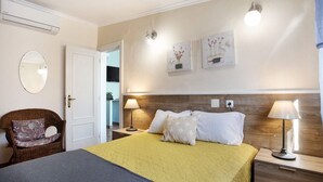 Een slaapkamer met een bed, twee nachtkastjes, een stoel, een spiegel en wandlampen.