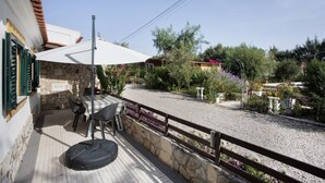 Een terras met een tafel en stoelen, een stenen muur en een grindpad.