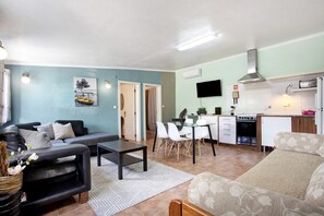 A living room with a sofa, coffee table, and a dining area with chairs and a table. - Holiday Home 'Casa 2' with Shared Pool, Wi-Fi and Air Conditioning (Vale da Pedra)