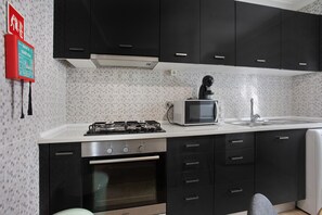 Une cuisine moderne avec des meubles de couleur noire, une cuisinière à gaz, un four à micro-ondes et un évier.