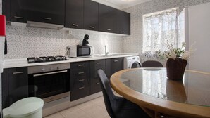 Una cocina moderna con armarios negros, un microondas, una estufa y una lavadora.