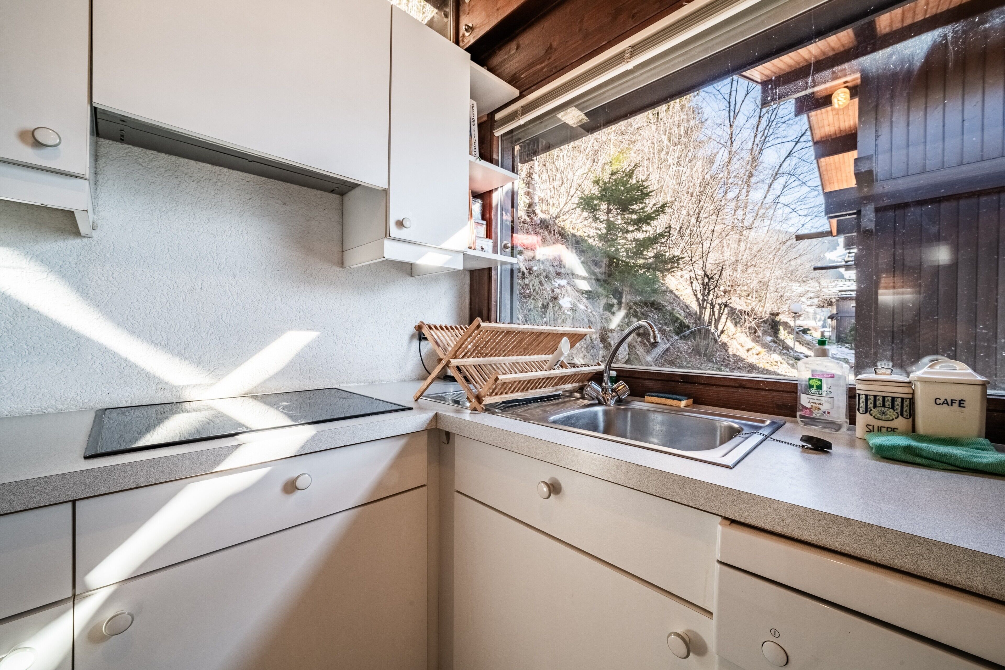 A kitchen with a window, a sink, and a dish rack.