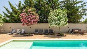 Une piscine avec des chaises longues et deux arbres en fleurs.