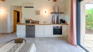 Une cuisine moderne avec des meubles blancs, une hotte en acier inoxydable, un lave-vaisselle et une fenêtre agrémentée d’un rideau rose.