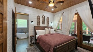 Un dormitorio con techo de madera, una cama grande, una ventana y vistas al exterior.